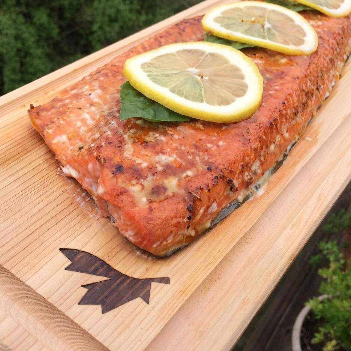 A wooden board with salmon and lemon slices on it.